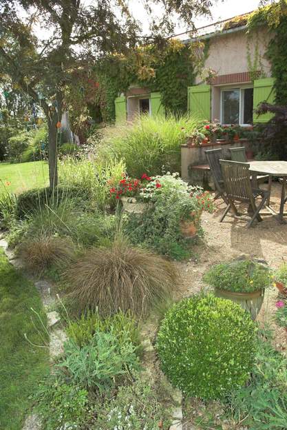 Terrasse fin d'été une vue caractéristique de la terrasse nord au début de l'automne. Les miscanthus sont fleuris, les carex prennent leur couleur d'hiver mais les potées des...